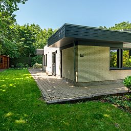 Zijaanzicht van vakantiehuis 16 - Zeebries in De Koog, Texel, omgeven door groen op de Waddeneilanden.