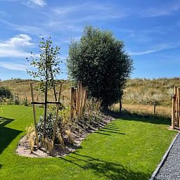 Natuurlijke omgeving van Duinvilla Wellness 5 in De Koog, Texel, met uitzicht op duinen en groene tuin.