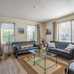 Gemuetliches Wohnzimmer im Ferienhaus Kamperfoelie 91, De Koog, Texel, mit bequemen Sofas und viel Licht.