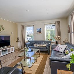 Geraeumige Sitzecke im Ferienhaus Kamperfoelie 91, De Koog, Texel, mit modernen Moebeln und grossen Fenstern.