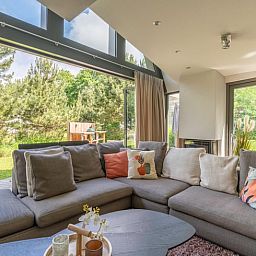 Blick aus dem Wohnzimmer des Ferienhauses in De Koog, Texel, mit gruenem Garten und gemuetlichen Sitzecken, ideal fuer einen ruhigen Urlaub.