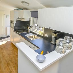 Moderne keuken in Chalet Bregkoog 215 Zandhuisjes op Chaletpark Bregkoog, De Koog, Texel met strakke werkbladen en veel licht.