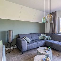 Modern living room in Holiday home in De Waal, Texel with comfortable corner sofa and views of nature.