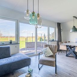 Bright living room in Holiday Home in De Waal, Texel with large windows and views of the terrace.