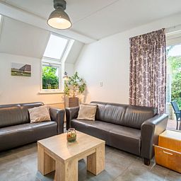 Ruime zitkamer in Huisje in De Waal, Texel met uitzicht op de tuin en toegang tot het terras.