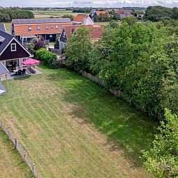 Luchtfoto van Vakantiehuisje in Den Burg op Texel, Waddeneilanden, met ruime tuin en terras, omgeven door groen en serene natuur.