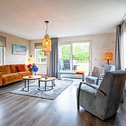 Gezellige woonkamer in Vakantiehuisje in Den Burg, Texel met modern interieur en uitzicht op de groene tuin.