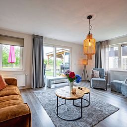 Gezellige woonkamer van Vakantiehuisje in Den Burg, Texel met comfortabele zithoek en uitzicht op de tuin, ideaal voor ontspanning.