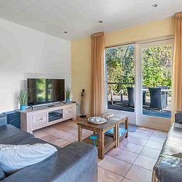 Gezellige woonkamer van Huisje in Den Burg, Texel met comfortabele banken en uitzicht op de tuin.