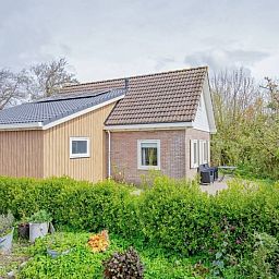 Seitenansicht des Ferienhauses 5 Persoons in Den Burg Texel, mit gruenem Garten auf den Watteninseln.
