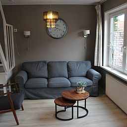 Stylish living room with sofa and clock in vacation home De Molen, Den Burg, Texel.