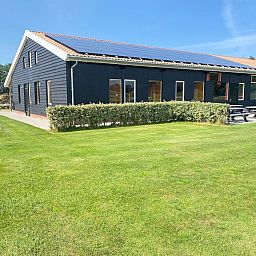 Sonniger Aussenbereich von De Stolp II rechts, Ferienhaus in Den Hoorn, Texel mit gruenem Garten.