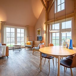 Gemuetliches Wohnzimmer im Ferienhaus Kamille in Den Hoorn auf Texel mit Holzinterieur und Blick auf die Natur der Watteninseln.