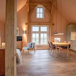 Innenraum des Ferienhauses Kamille in Den Hoorn, Texel, mit grosszuegigem Wohnzimmer und Blick auf die Natur der Watteninseln.