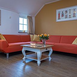 Gemuetliches Wohnzimmer im Apartment Yellow, einem Ferienhaus in Den Hoorn, Texel, mit bequemen Sitzgelegenheiten und rustikaler Einrichtung.