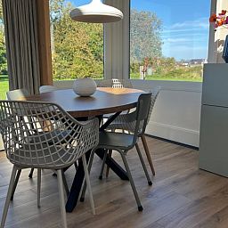 Essecke im Ferienhaus in Den Hoorn, Texel, mit Blick auf die gruene Landschaft.
