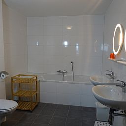 Geraeumiges Badezimmer mit Badewanne und Doppelwaschbecken in De Dors Ferienhaus Den Hoorn Texel.
