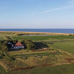 Holzschild mit der Aufschrift "Gaestehaus" an einem Ferienhaus in Oosterend, Texel, umgeben von Gruenanlagen.