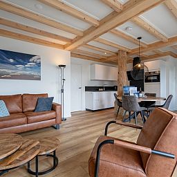 Cozy living room of Apartment C, Texel, with wooden beams and modern furnishings.
