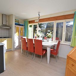 Eethoek in Vakantiehuis De Nagtegaal 15, De Wulk, De Dennen, Texel, met grote ramen en veel natuurlijk licht.