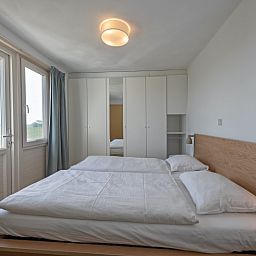 Slaapkamer met tweepersoonsbed in Huisje 7 in De Dennen, Texel biedt comfort en een prachtig uitzicht op de Waddeneilanden.