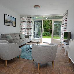 Lichte woonkamer van Vakantiehuis de Parel 182 in De Dennen, Texel met uitzicht op de tuin.
