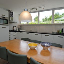 Eetkamer in Vakantiehuis de Parel 182, De Dennen, Texel met houten tafel en stijlvolle stoelen.