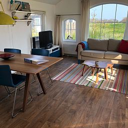 Gezellige woonkamer in Vakantiepark De Bremakker - Akkerveld 14, De Dennen, Texel. Comfortabele zithoek met uitzicht op groene omgeving.