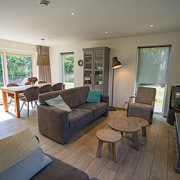 Helles Wohnzimmer des Ferienhauses de Parel 150 in De Dennen, Texel mit Blick auf den Garten.