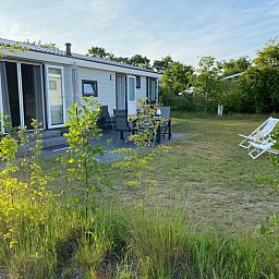Geniet van de natuur rondom Vakantiepark de Bremakker - Bosveld 148, De Dennen, Texel met een uitnodigende buitenruimte en ligstoelen.