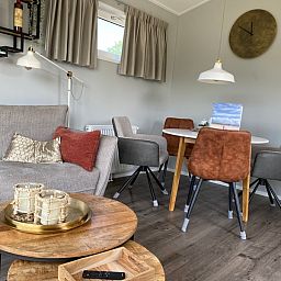 Eetgedeelte van Vakantiepark de Bremakker - Bosveld 148 in De Dennen, Texel met stijlvolle stoelen en warme sfeer.