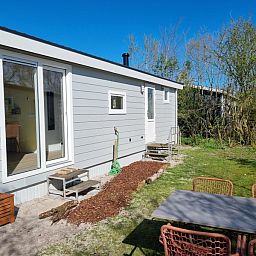 Terras en tuin van vakantiehuis op Vakantiepark de Bremakker, Bosveld 135, De Dennen, Texel, ideaal voor buiten dineren.