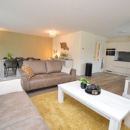 Offenes Wohnzimmer und Kueche im Ferienhaus De Nagtegaal 23, De Dennen Texel, mit moderner Ausstattung.