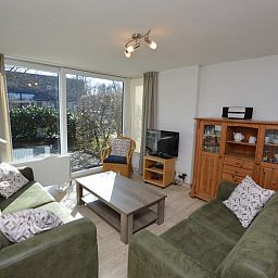 Helle Sitzecke im Ferienhaus de Parel 198 in De Dennen, Texel, mit Blick auf die gruene Umgebung und bequemen Moebeln.