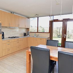 Moderne Kueche im Ferienhaus de Parel 198 in De Dennen, Texel, mit Holzschraenken und Esstisch, ideal fuer gemuetliche Mahlzeiten.