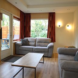 Comfortabele zithoek in Vakantiehuis De Nagtegaal 19, De Dennen Texel met grote ramen en tuinzicht.