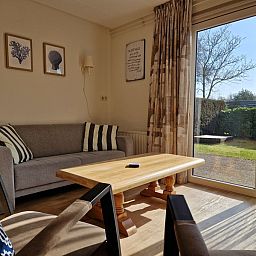 Gemuetliches Wohnzimmer mit Blick auf den Garten im Bungalowpark Uterste Coogh, Bungalow 116 in De Dennen, Texel.