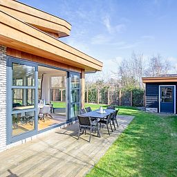 Side view of Holiday Home De Vlinder in De Dennen, Texel, with sunny terrace and green garden.
