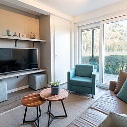 Comfortabele zithoek met tv in Appartement Bos en Duin 12, De Dennen, Texel, perfect voor ontspanning.