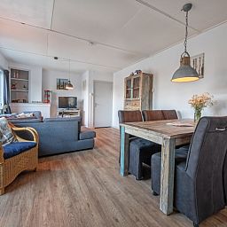 Gemuetliches Wohnzimmer des Ferienhauses Flora in De Dennen, Texel. Komfortable Sitz- und Essecke im gemuetlichen Ferienhaus auf den Watteninseln.