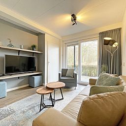 Stilvolles Wohnzimmer des Appartements Bos en Duin 14, Texel, mit Flachbildfernseher und Zugang zur Terrasse.