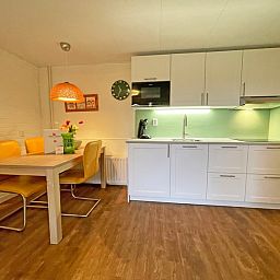 Moderne keuken in Appartement Bos en Duin 15, De Dennen, Texel met eethoek en sfeervolle verlichting.