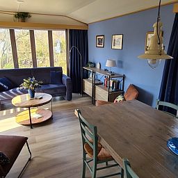 Innenraum des Ferienhauses im Vakantiepark De Bremakker, Texel, mit einem gemuetlichen Wohnzimmer und viel Licht.