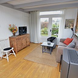 Geraeumiges Interieur des Bungalows Uterste Coogh 122, Texel, mit Zugang zu einer sonnigen Terrasse.