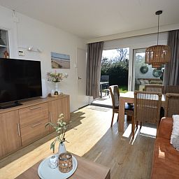 Gezellige zithoek in Bungalow Uterste Coogh 96, De Dennen, Texel, met uitzicht op de tuin en veel natuurlijk licht.