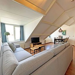 Helles Wohnzimmer des Appartements Bos en Duin 33, De Dennen, Texel mit grossen Fenstern und Blick auf die Umgebung.