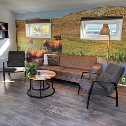 Gemuetliches Wohnzimmer im Ferienpark De Bremakker - Bosveld 128, De Dennen, Texel, mit komfortabler Sitzecke und naturbezogener Inneneinrichtung.