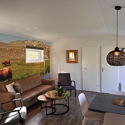 Gemuetliches Wohnzimmer im Ferienpark De Bremakker - Bosveld 128, De Dennen, Texel, mit komfortabler Sitzecke und Naturthema.
