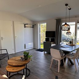 Gemuetliches Wohnzimmer im Ferienhaus Vakantiepark de Bremakker, Bosveld 128, De Dennen, Texel, mit moderner Einrichtung und Blick auf den Garten.
