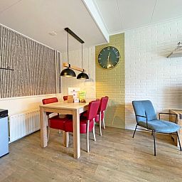 Eetkamer van Appartement Bos en Duin 10, Texel met houten tafel en kleurrijke stoelen.